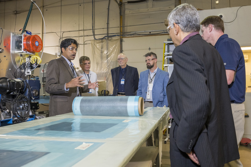 Dr. Yarlagadda in brown jacket explain TuFF fiber rolls to attendees around a table.