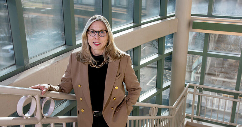 Nancy Sottos stands in a glass enclosed stairwell.